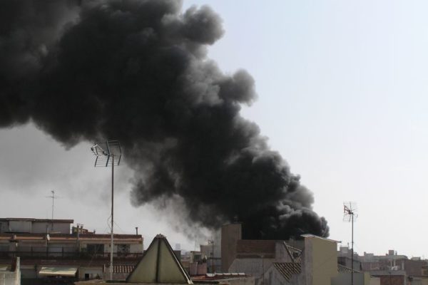 Columna de fum molt negra darrere d'uns edificis