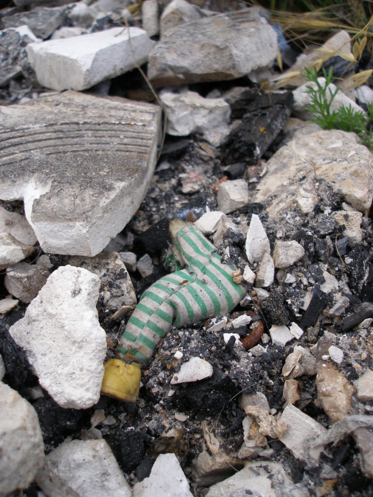 Nino amb vestit de ratlles verdes i blanques colgat per la cendra i pedres