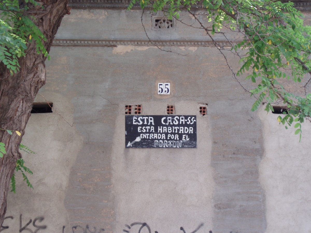 Casa tapiada amb un rètol que posa "Esta casa -55- está habitada. Entrada por el portón"