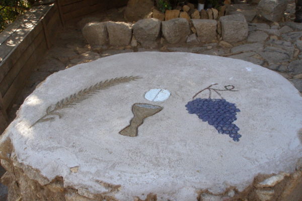 Altar fent amb pedres i ciment amb gravats d'una espiga, el calze i l'hòstia i raïm
