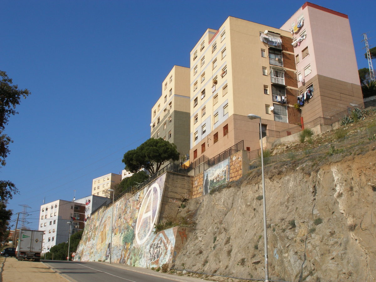 Vista d'edificis del Singuerlin des d'un carrer que fa molta pujada, els blocs de pisos estan sobre roca