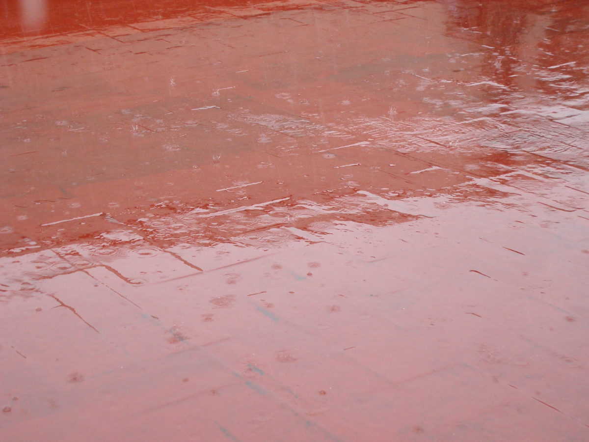 Terra del terrat de color vermell on hi cauen gotes de pluja