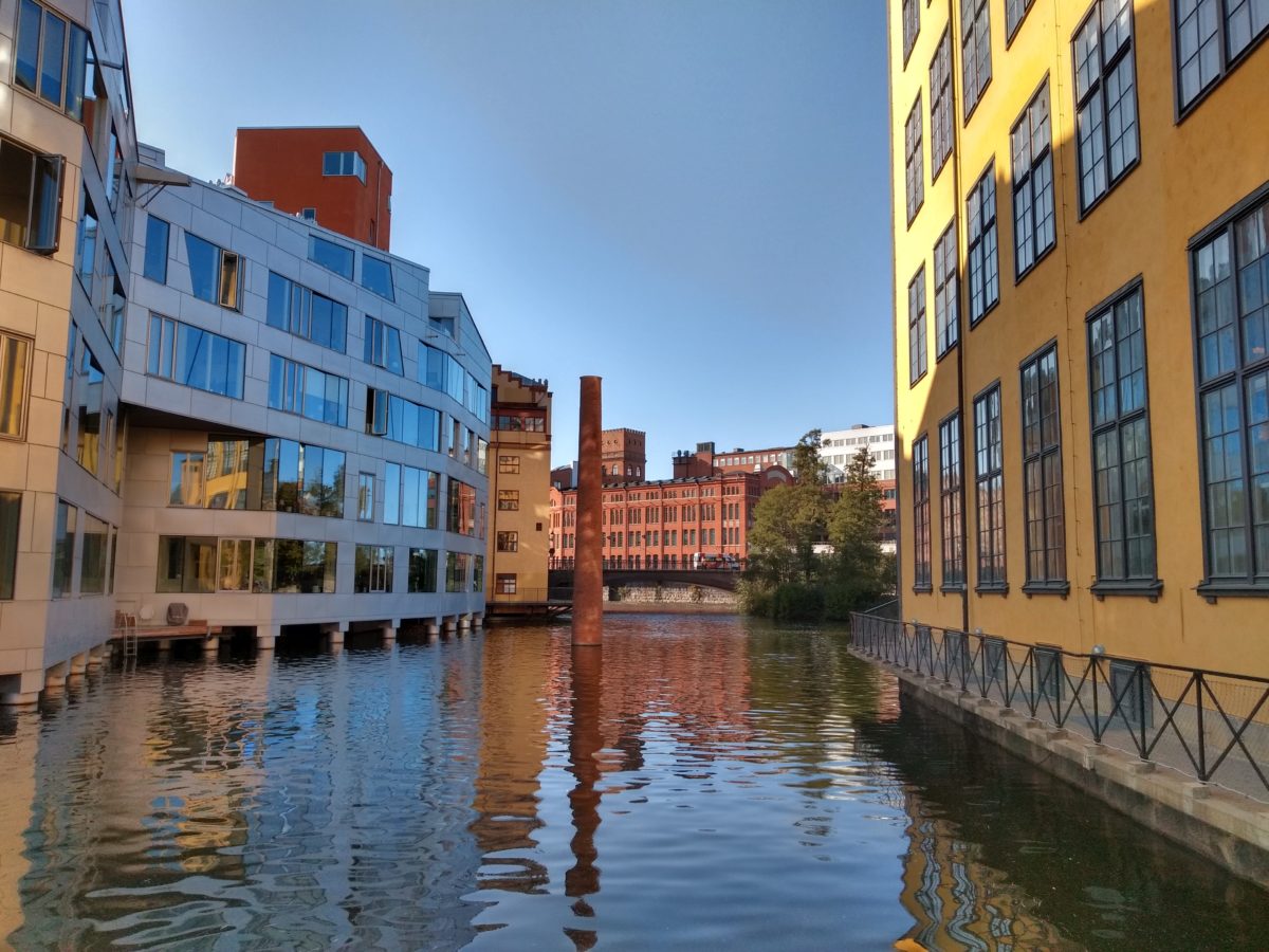 Canal que passa entre dos edificis, talment com un carrer, amb una xemeneia al mig que sobresurt de l'aigua,