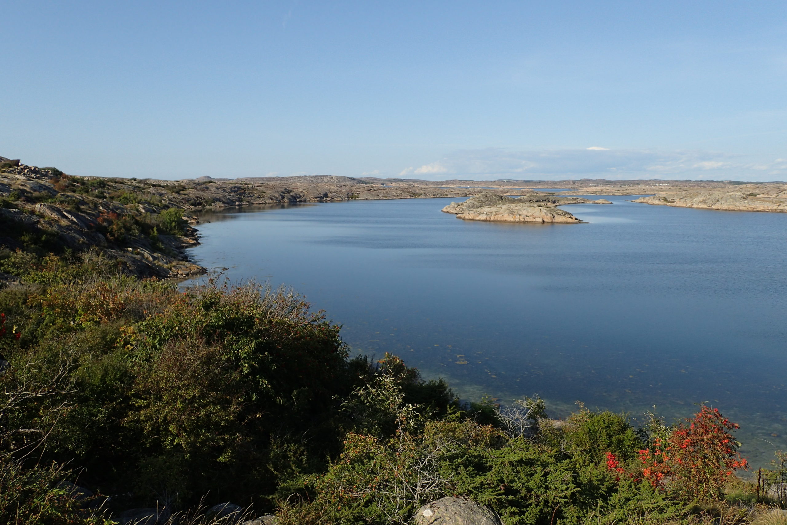 Vista des de dalt del turoent de roca amb el mar molt calmat i les roques de l'altra banda que l'envolten.