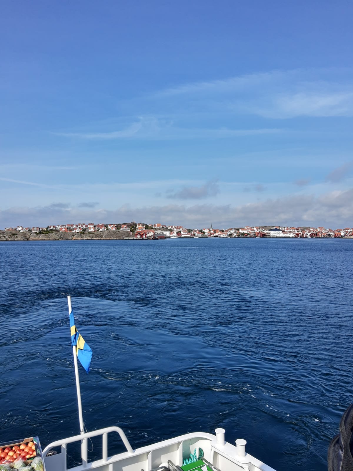 Durant el trajecte, amb la costa de fons, una banera sueca del vaixell en primer terme